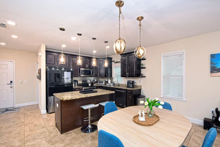 Kitchen featuring dark wood cabinetry, granite countertops, tile flooring, and stainless steel appliances