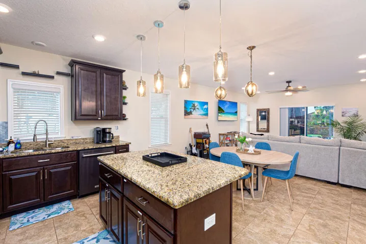 Kitchen featuring dark wood-finish cabinetry, granite countertops, and a center island with pendant lighting