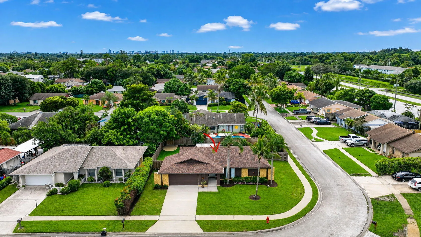 Single-story residence on a curved street with an attached garage, featuring a shingled roof, mature landscaping, and an expansive front lawn
