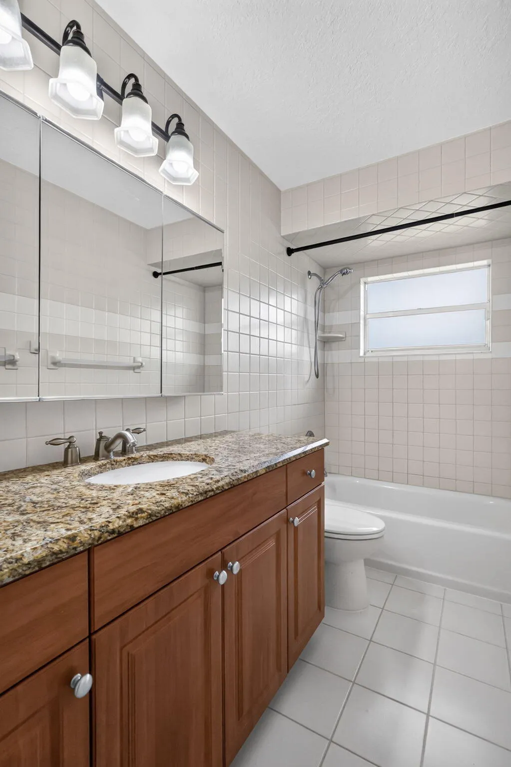 Wood-finish vanity with a granite-style countertop, integrated sink, and chrome faucet