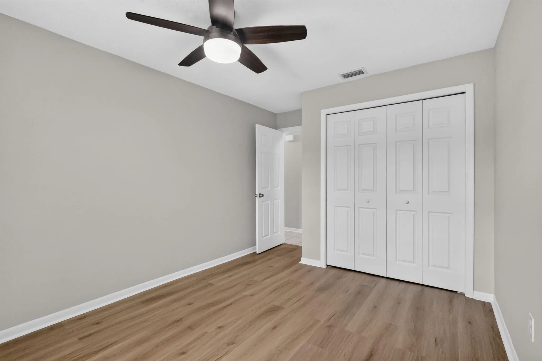 Room featuring wood-finish flooring, light gray wall paint, and white trim