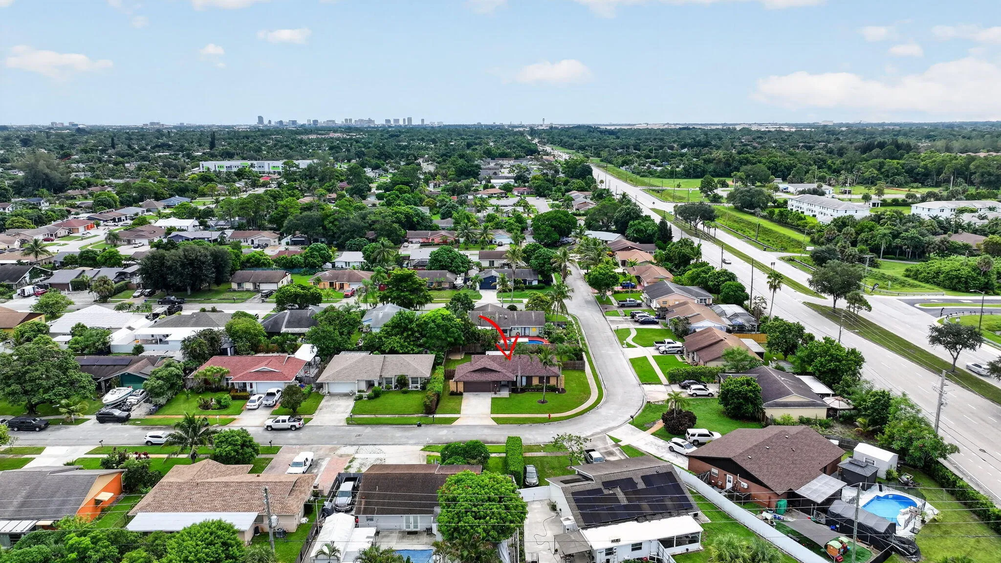 Residential neighborhood featuring mature trees and a distant urban skyline