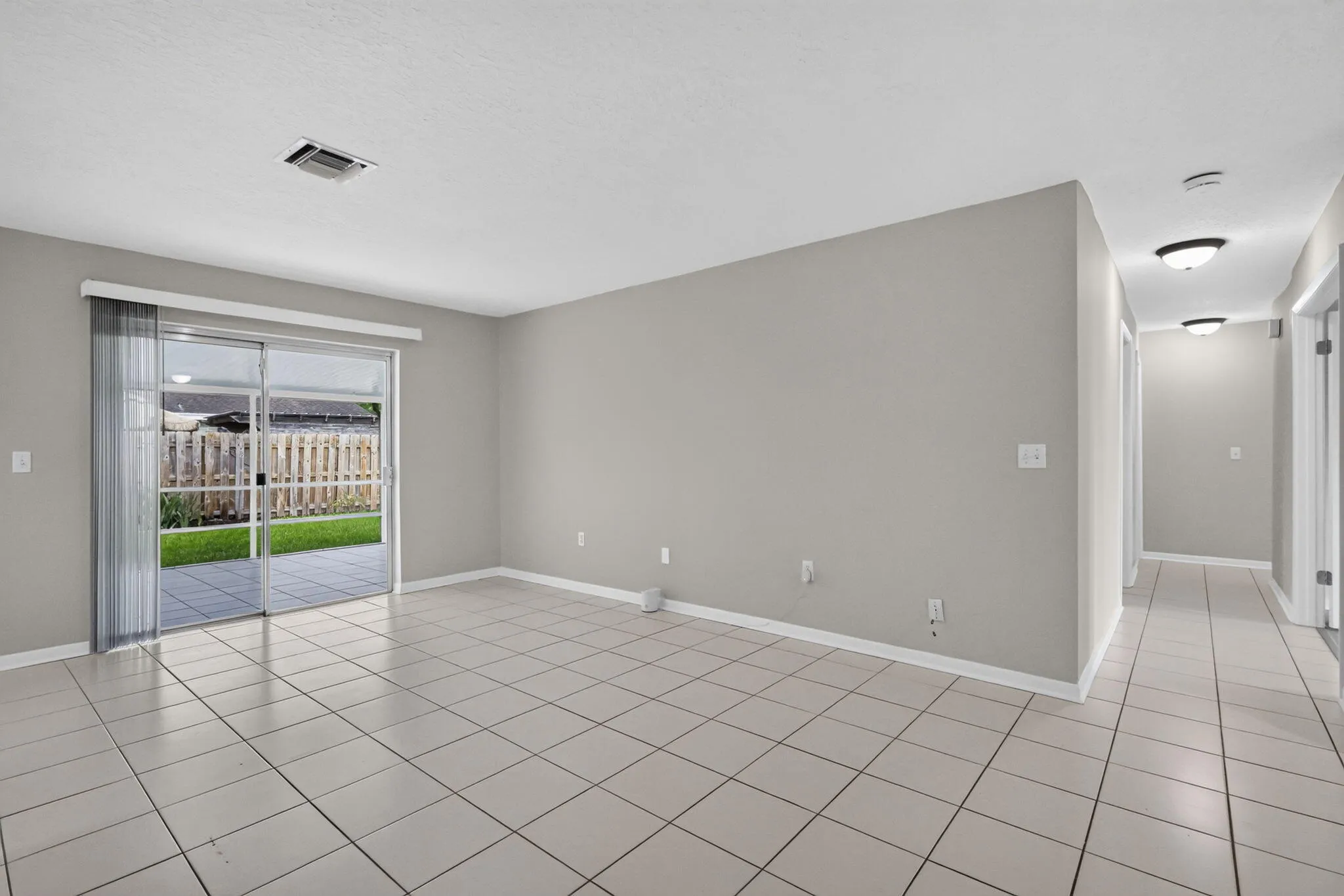 Tile flooring throughout, with a neutral wall color, and a sliding glass door providing access to an outdoor patio area