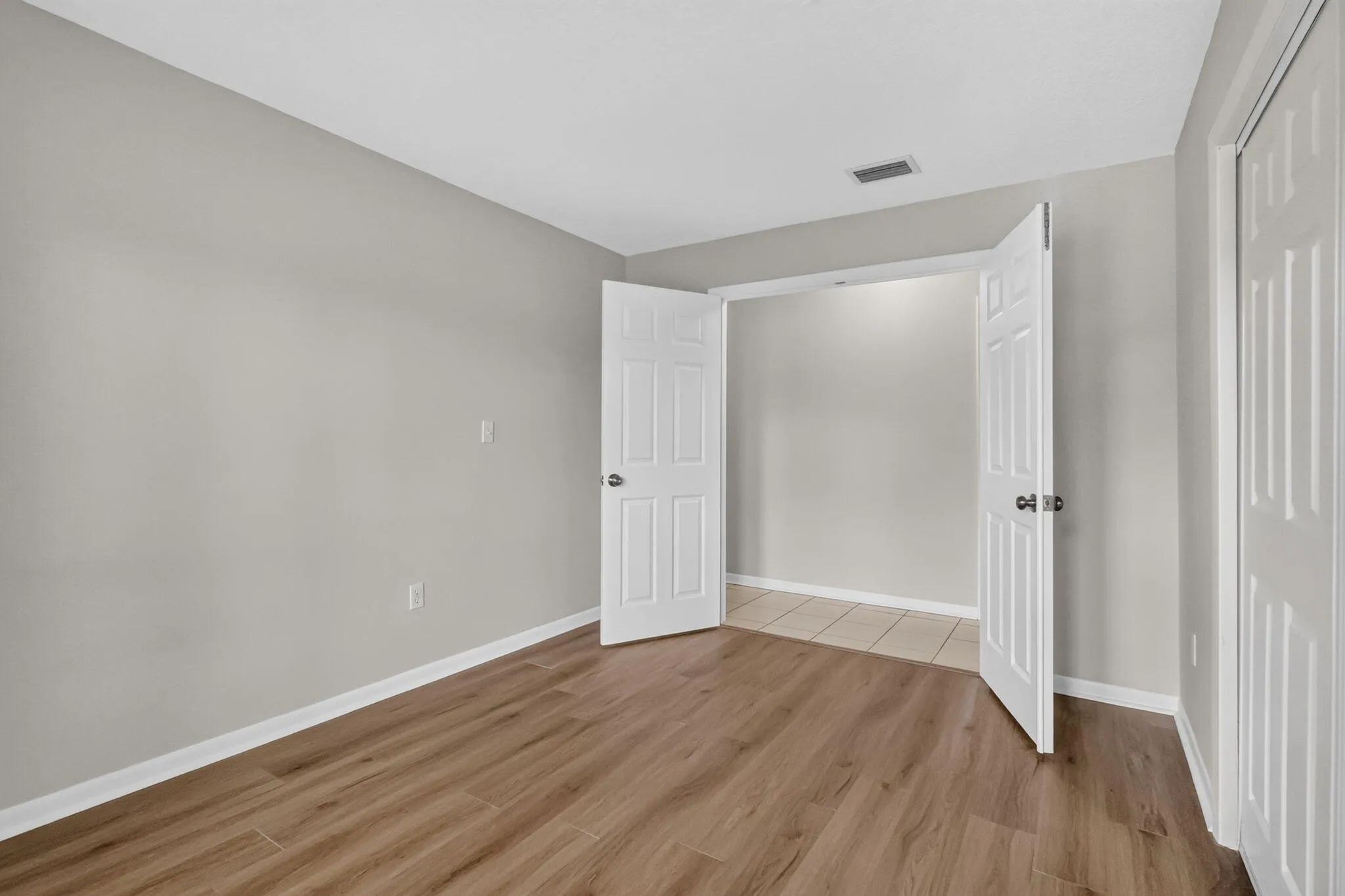 Wood-finish flooring, light gray wall paint, and white trim throughout