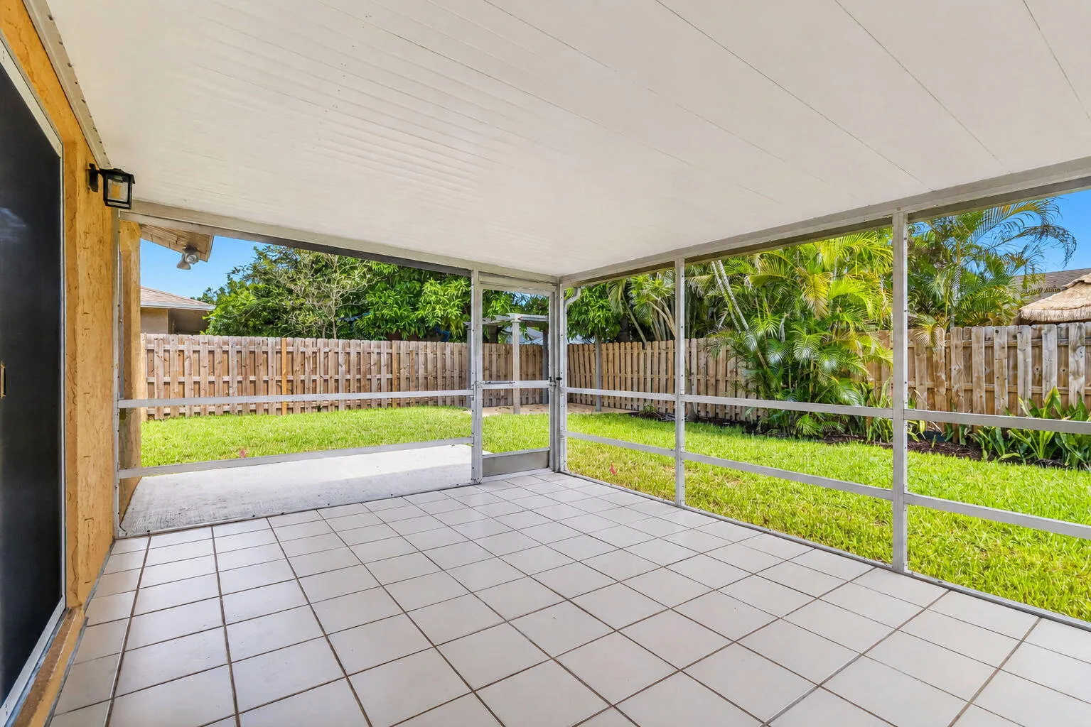 Screened patio with white tile flooring, white ceiling, and exterior wall-mounted lighting