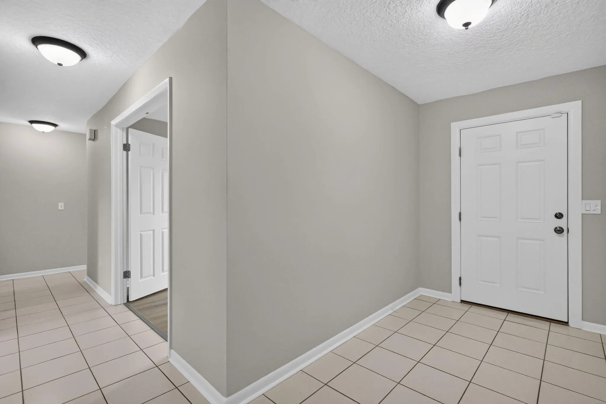 Tiled flooring, overhead lighting, paneled doors, and light gray wall finishes