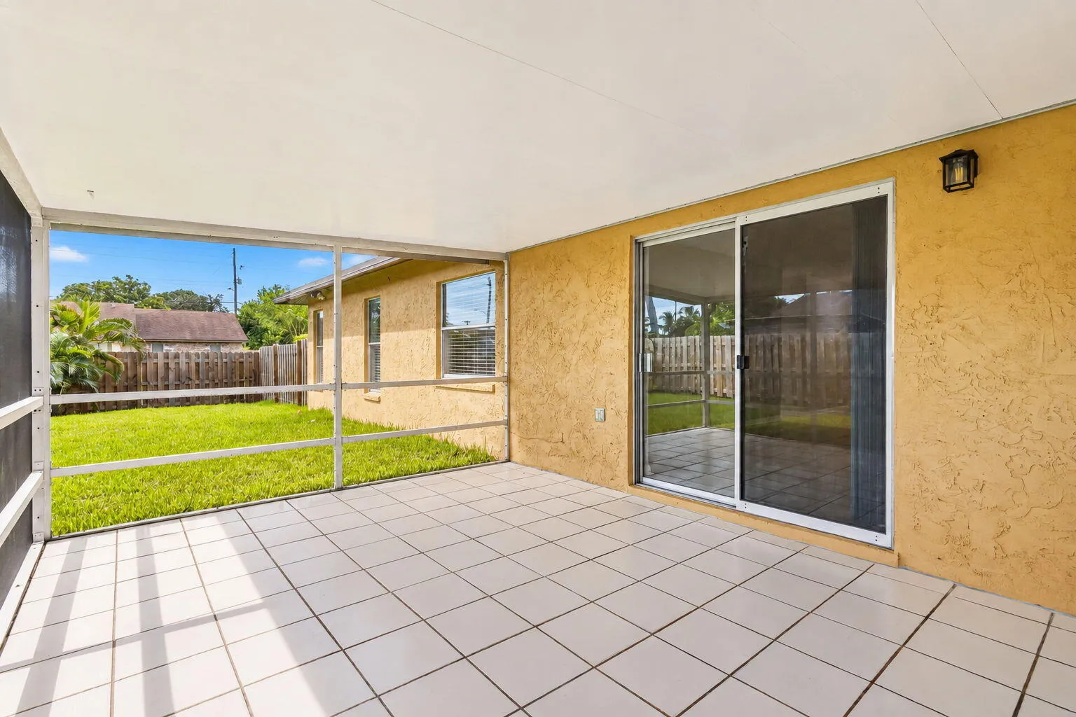 Screened patio with white tile flooring and a stucco exterior