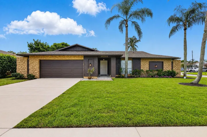 Stone veneer facade with wood-paneled accents, a brown garage door, and a concrete driveway