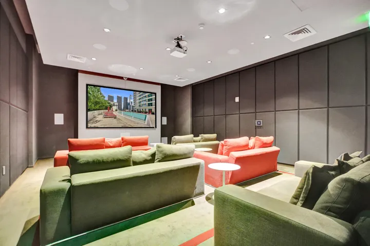 Dedicated media room featuring a large projection screen, recessed ceiling lighting, and integrated sound system