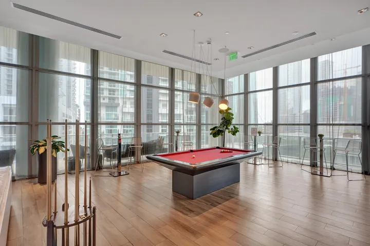 Expansive room featuring floor-to-ceiling windows, wood-finish flooring, recessed lighting, and modern pendant light fixtures