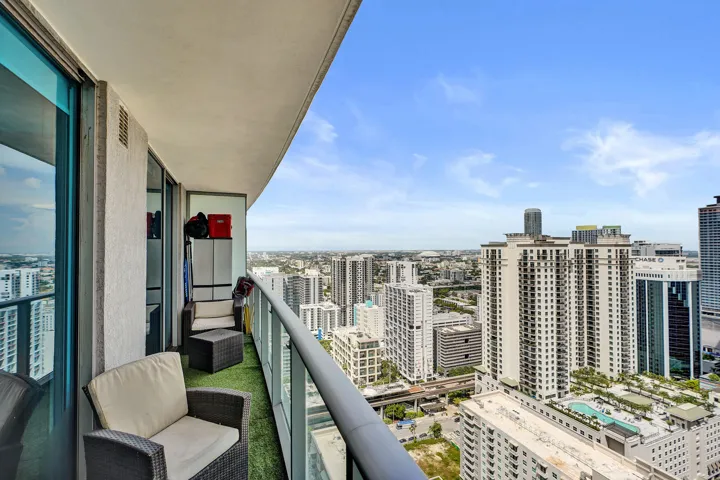 Balcony featuring glass railings, a concrete ceiling, and large sliding glass doors