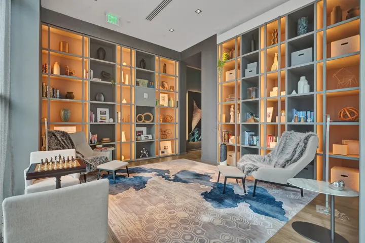 Integrated shelving with backlighting, recessed ceiling lighting, wood-finish flooring, and a marble-top accent table