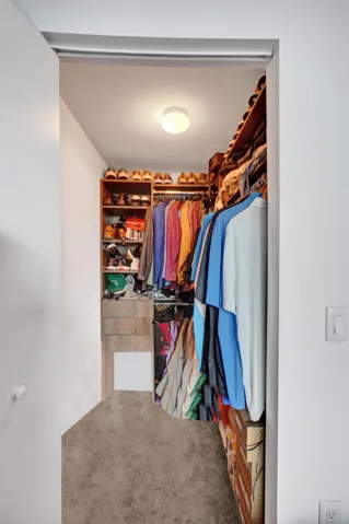 Walk-in closet featuring built-in wood shelving, hanging rods, and recessed ceiling lighting