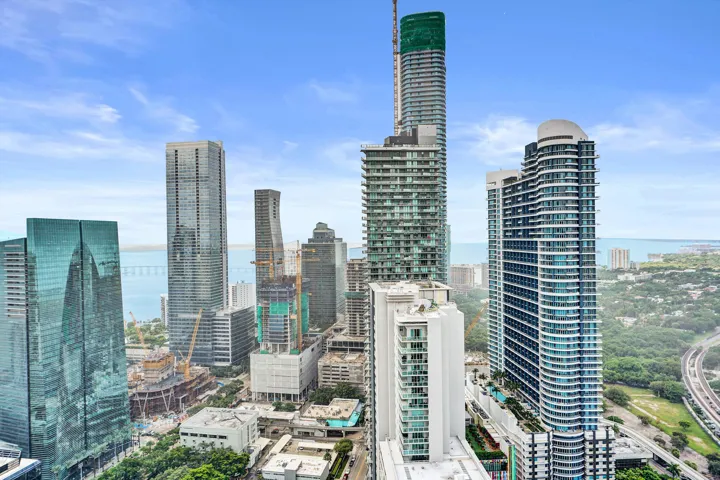 Cityscape with multiple high-rise buildings, urban infrastructure, and distant water