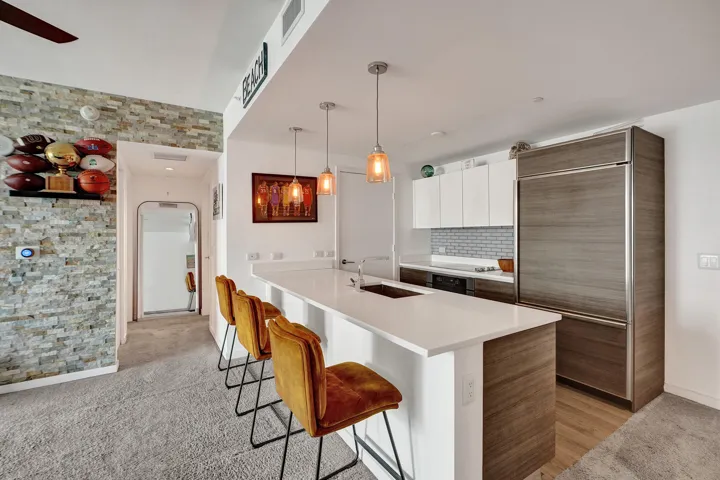 Kitchen island with a white countertop and integrated sink, complemented by wood-finish lower cabinetry