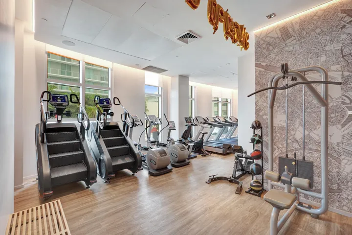 Fitness center featuring wood-finish flooring, large windows, and a dedicated accent wall