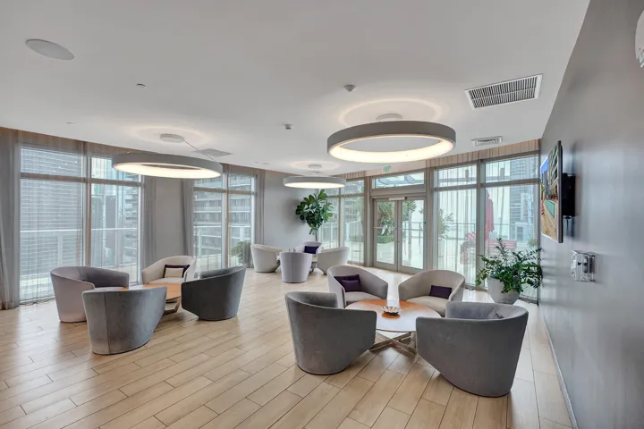 Expansive room featuring wood-finish flooring, full-height windows, recessed lighting, and modern circular pendant lights