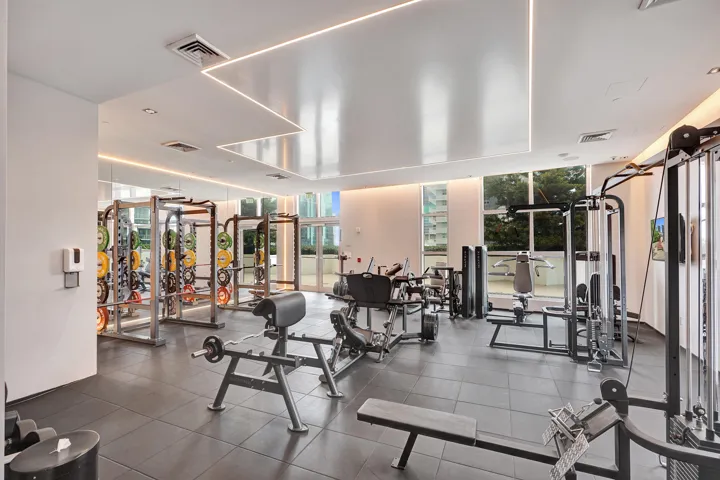 Spacious fitness center featuring recessed lighting, high ceilings, large windows, and dark rubber flooring