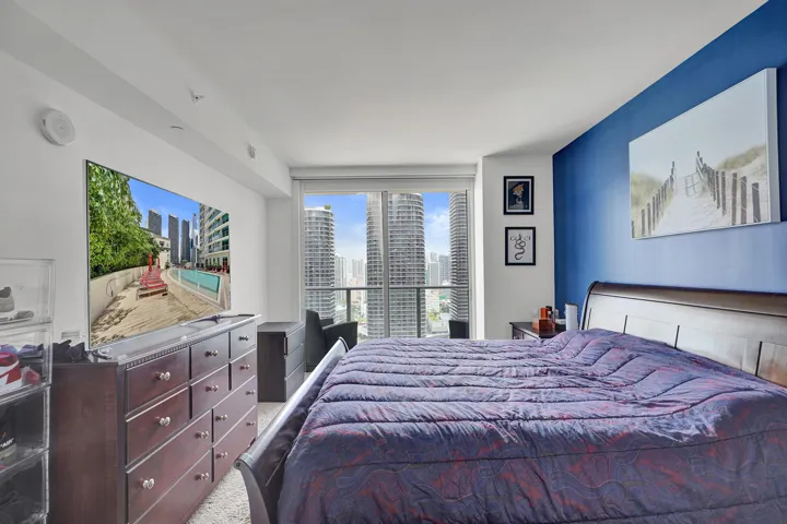 Floor-to-ceiling windows with urban skyline, recessed ceiling lighting, and a prominent accent wall