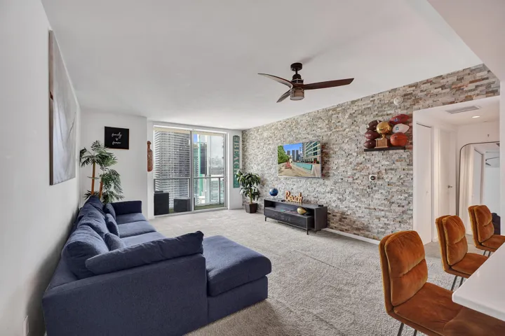 Textured accent wall, ceiling fan, sliding glass doors, carpet flooring, and recessed lighting
