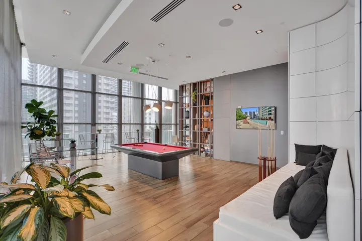 Expansive common area featuring floor-to-ceiling windows, wood-finish flooring, recessed lighting, and a built-in wall unit