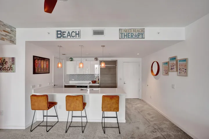 Kitchen island with pendant lighting, white cabinetry, light-toned countertops, and subway tile backsplash