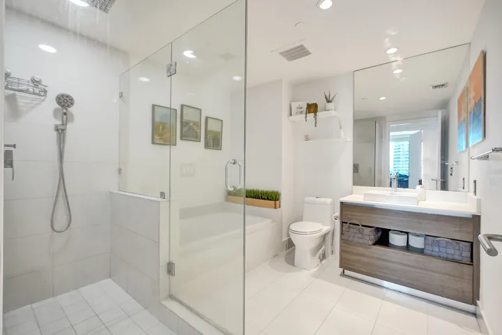 Enclosed glass shower with a built-in bench, rainfall showerhead, and handheld sprayer