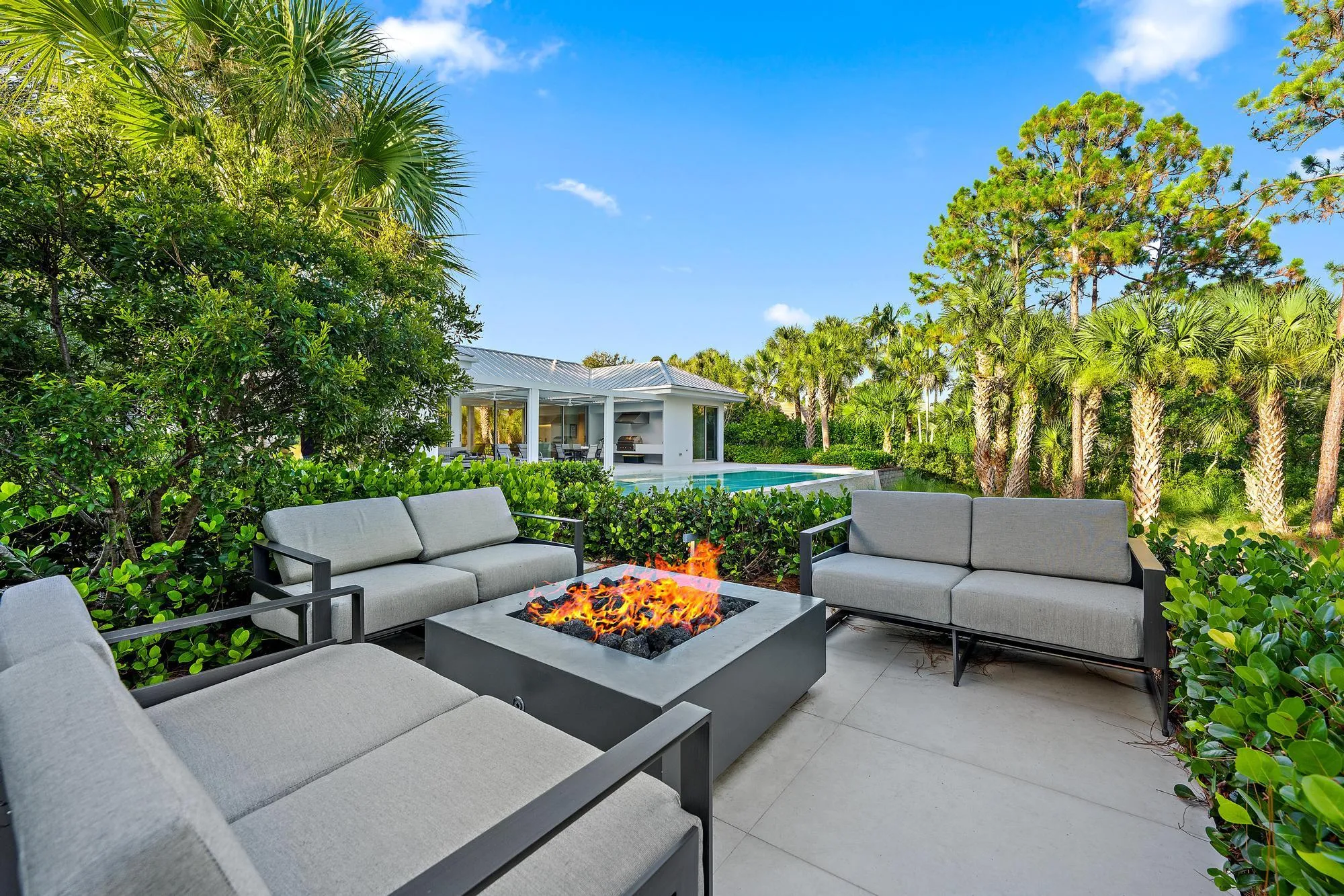 Expansive outdoor patio with a built-in fire pit, surrounded by lush landscaping and mature trees