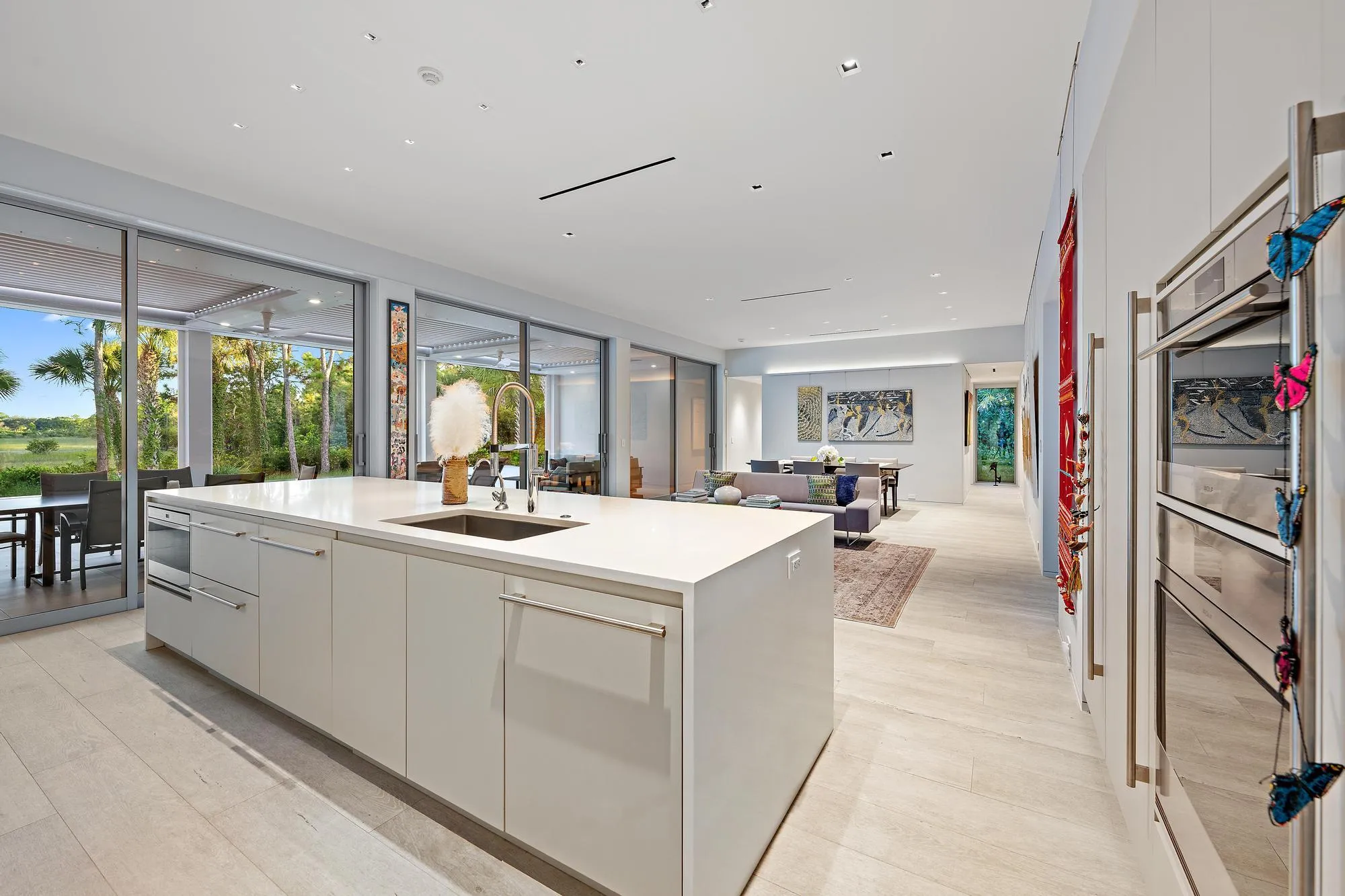 Contemporary kitchen anchored by a white cabinetry island with waterfall countertop, stainless steel appliances, and light wood-finish flooring