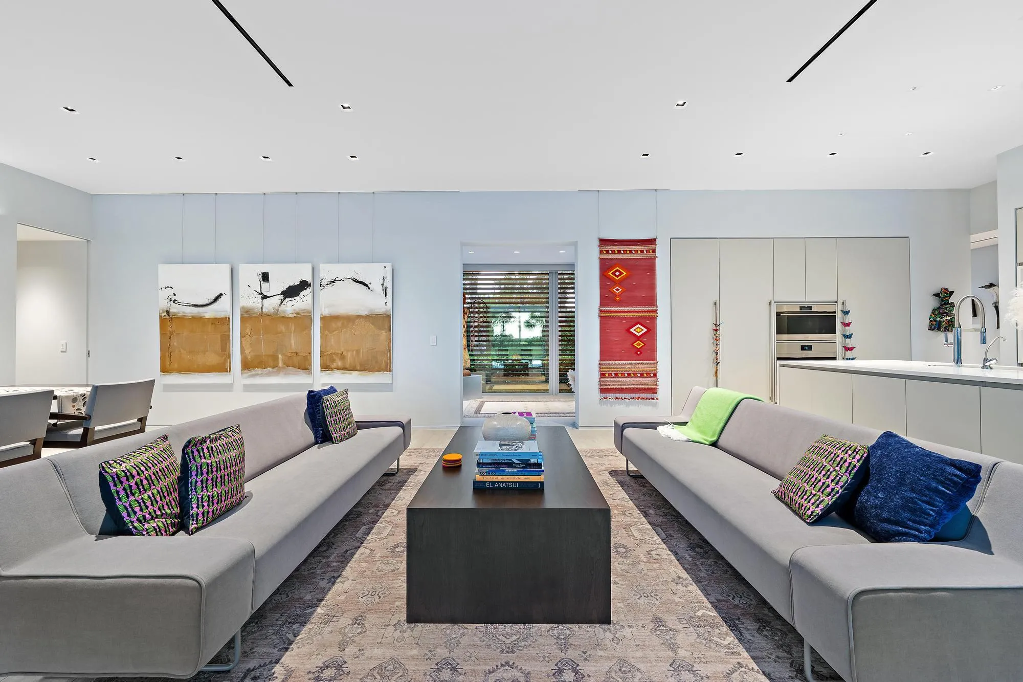 Open-concept living space with recessed lighting and a sleek kitchen featuring integrated appliances and an island with a sink