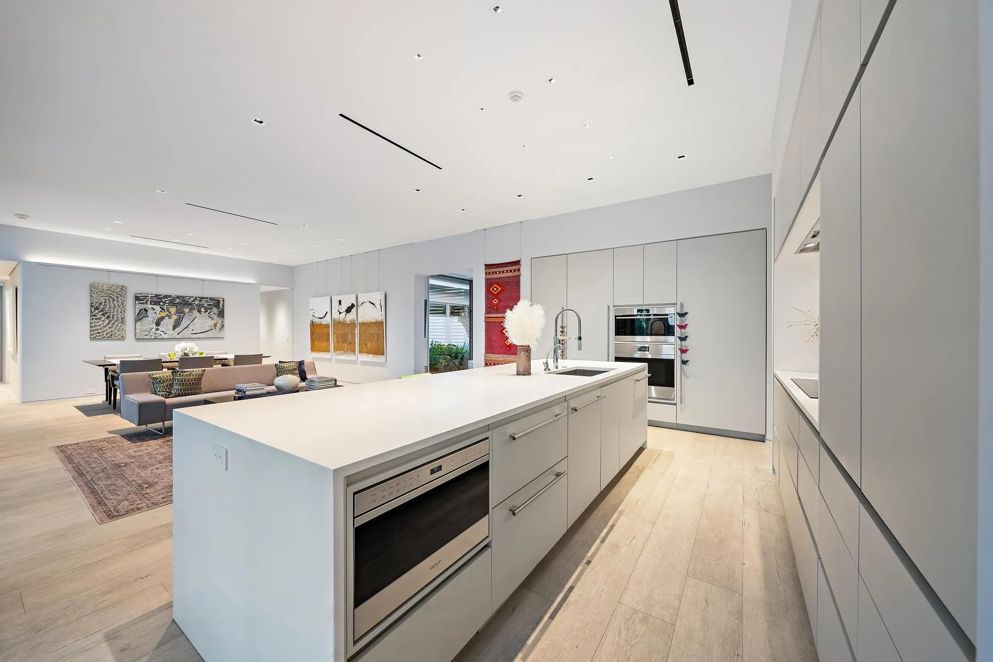 Open-concept kitchen with a large island featuring a built-in microwave, integrated appliances, and light wood-finish flooring