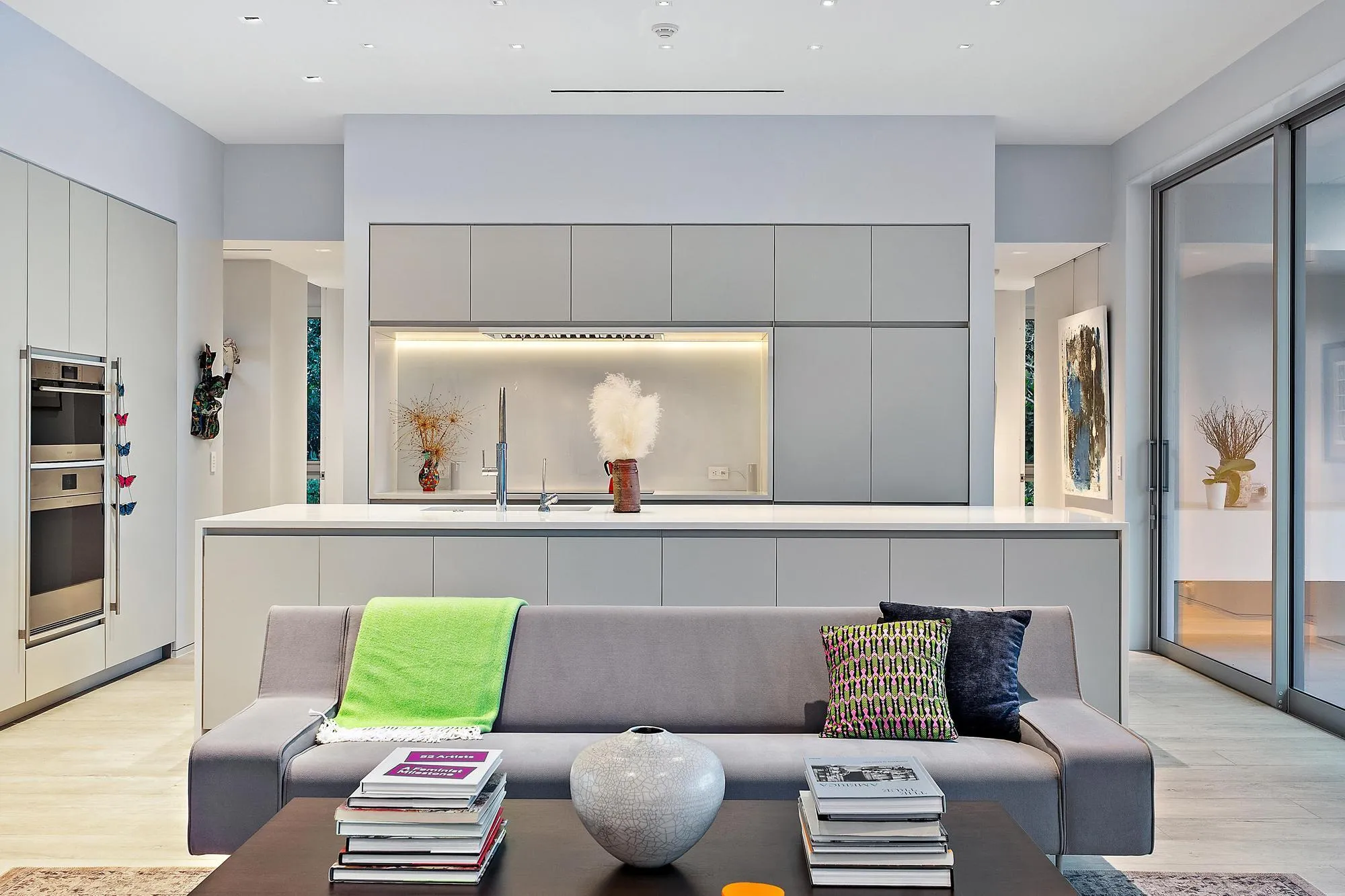 Contemporary kitchen with integrated appliances, extensive cabinetry, a large center island, under-cabinet lighting, and wood-finish flooring