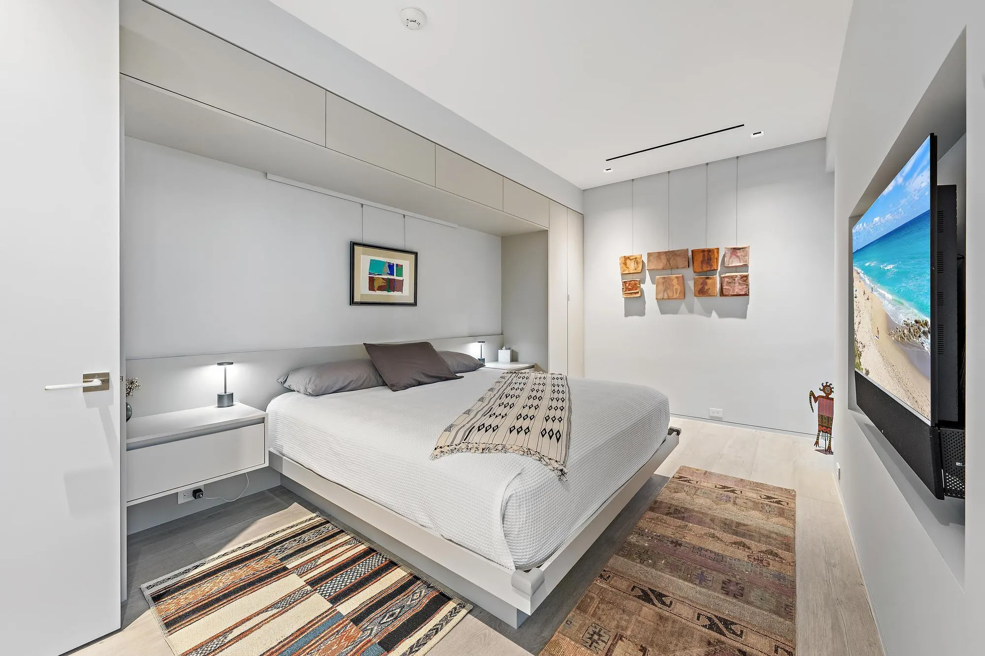 Integrated headboard with built-in side tables, recessed lighting, and upper cabinetry