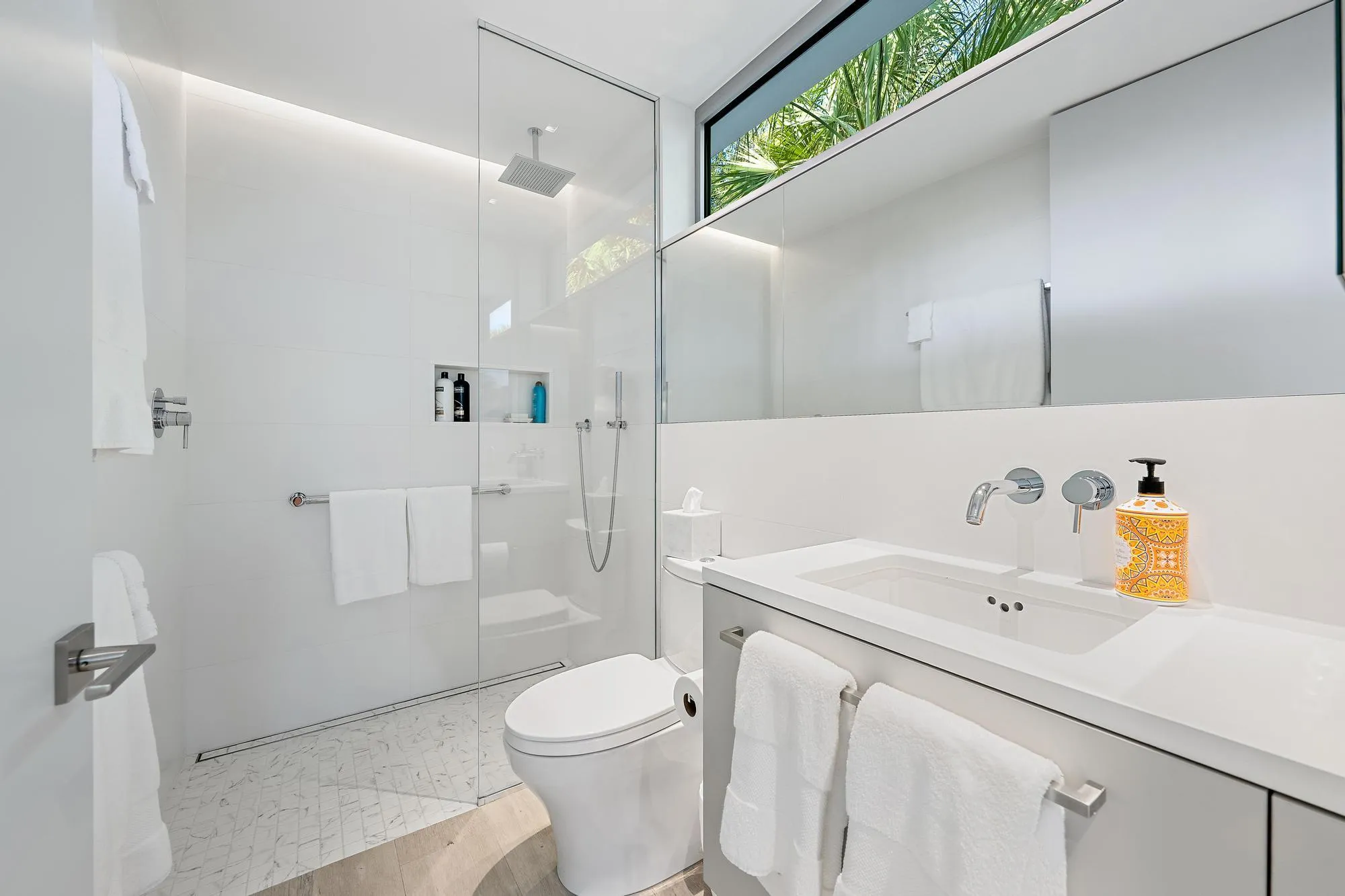 Floating vanity with an integrated rectangular sink, wall-mounted faucet, and a large mirror