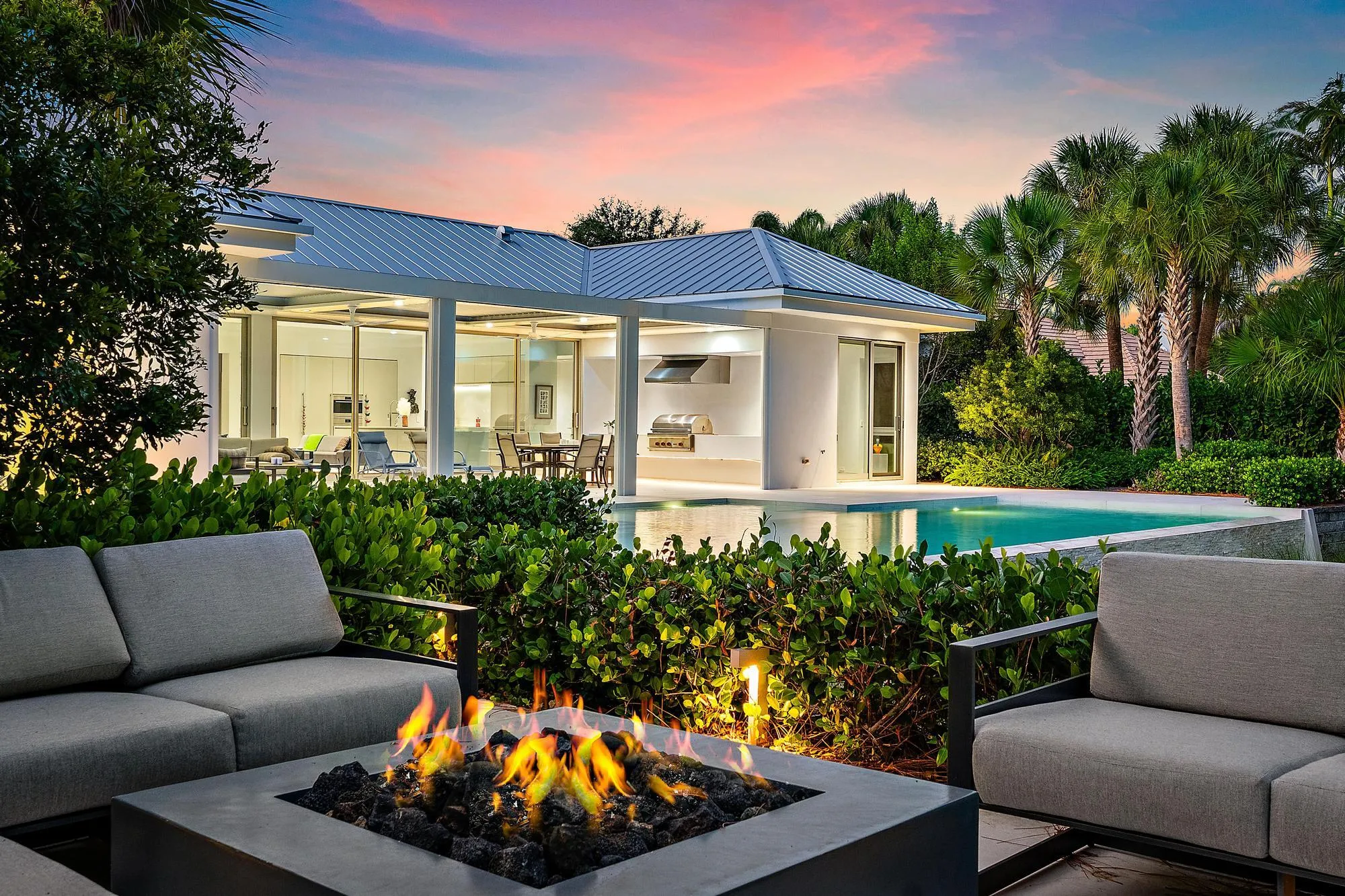 Modern residence with clean-lined architecture and metal roof, featuring expansive glass sliding doors and a covered porch