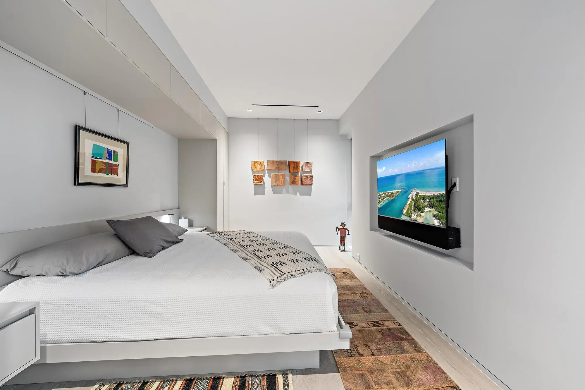 Recessed wall-mounted television, light wood-finish flooring, and built-in lighting
