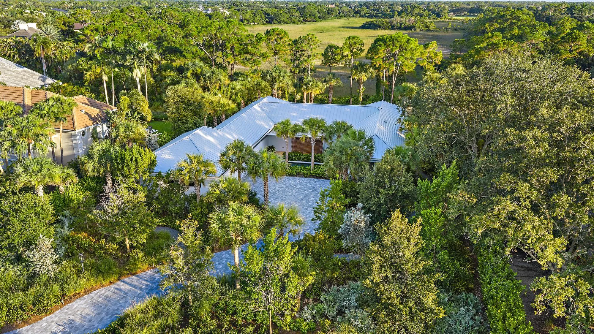 Expansive property featuring lush, mature landscaping and a metal roof