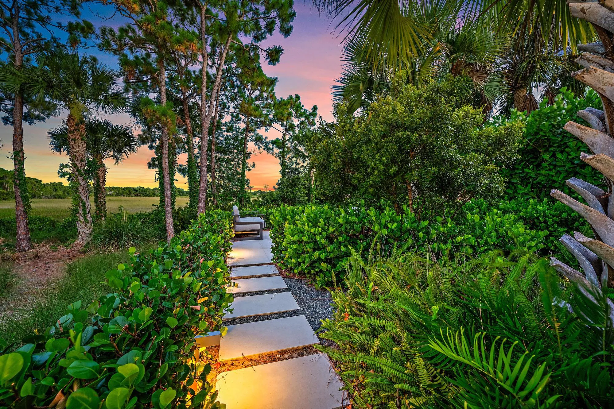 Paver pathway with integrated lighting, surrounded by diverse plantings including palm trees and lush greenery