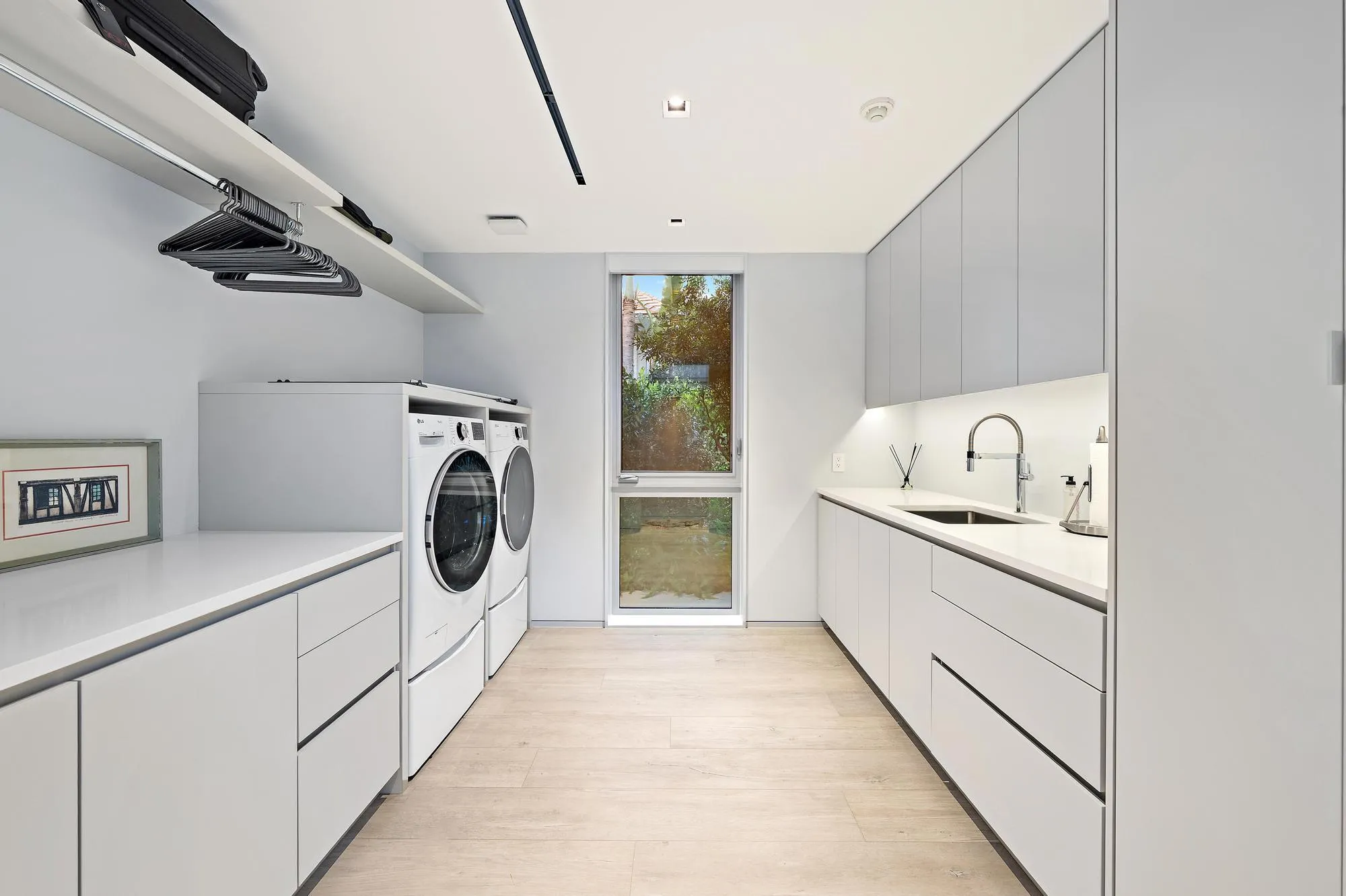 Integrated laundry appliances, extensive counter space, sleek cabinetry, recessed lighting, and wood-finish flooring