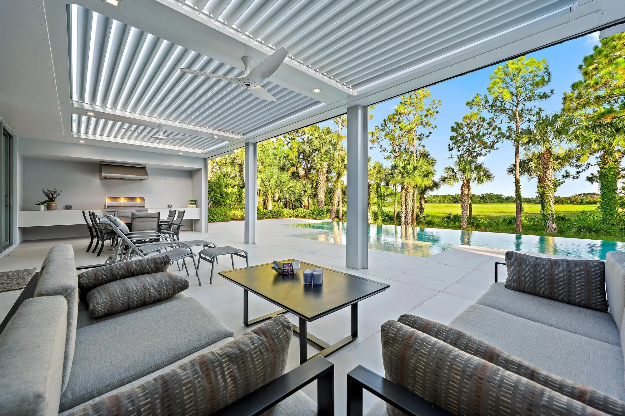 Expansive covered patio featuring a built-in outdoor kitchen, recessed lighting, and ceiling fan
