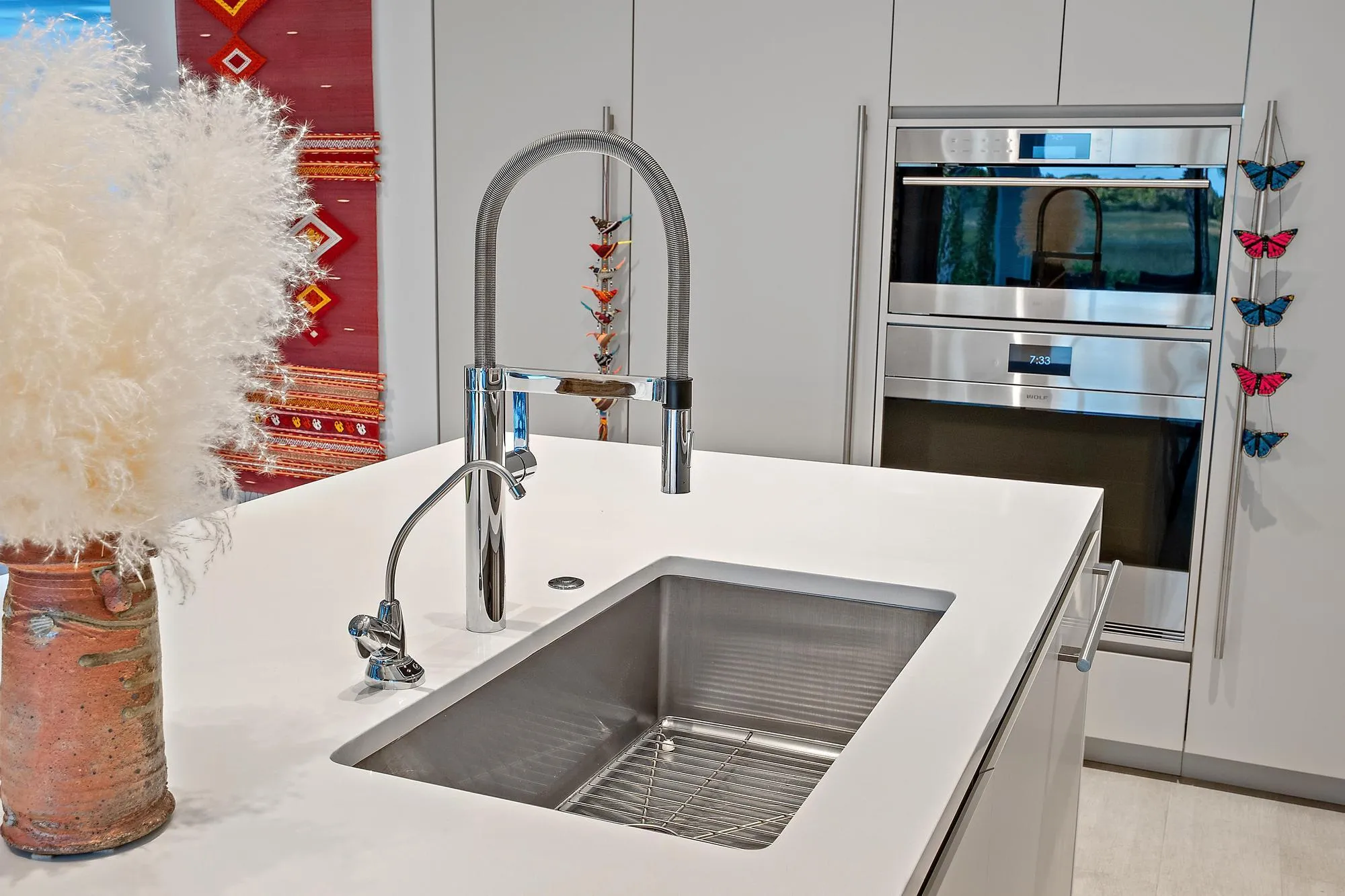 Integrated stainless steel sink with a high-arc faucet, solid surface countertop, and built-in double ovens