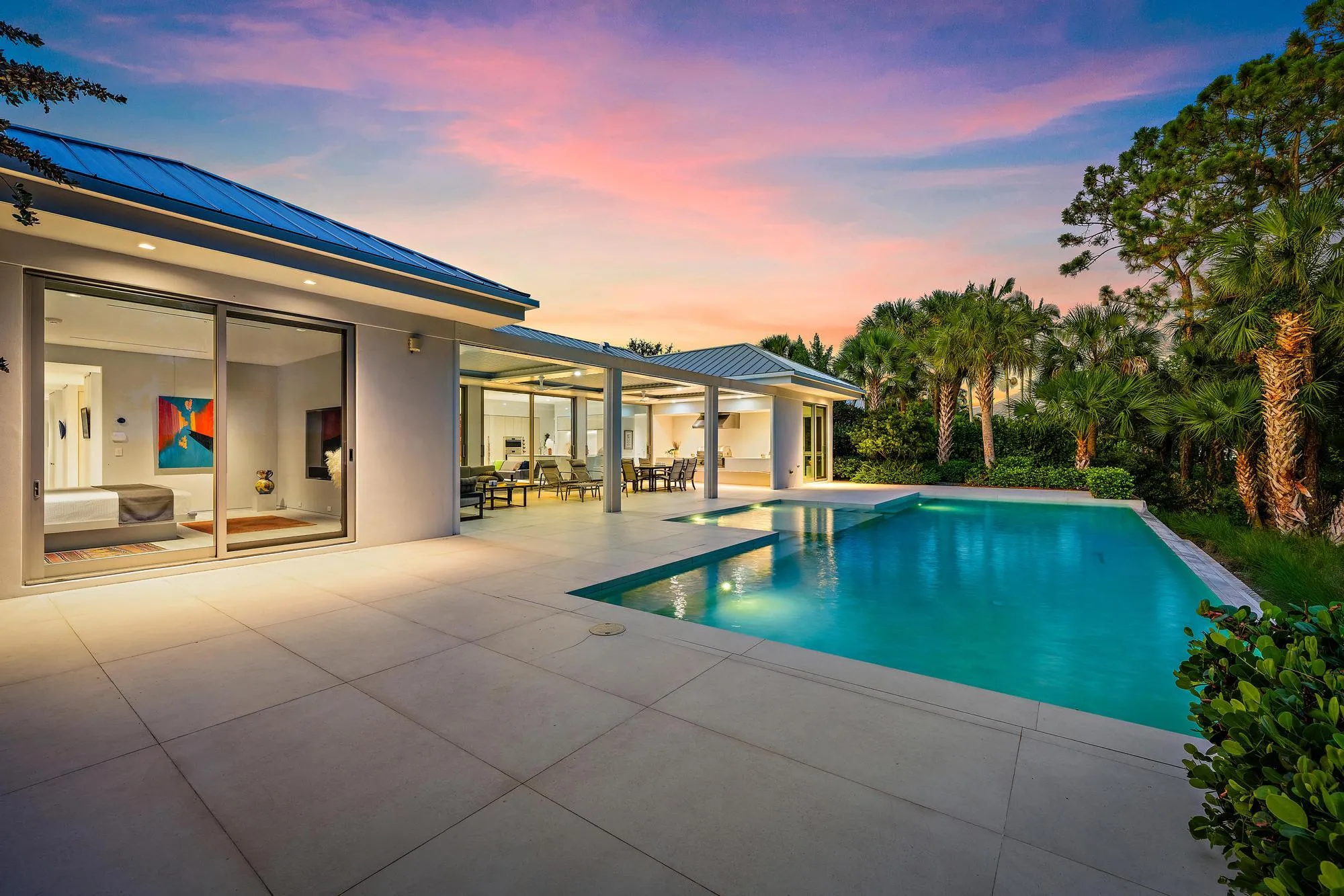 Expansive outdoor living area featuring a large swimming pool, covered patio, and lush tropical landscaping