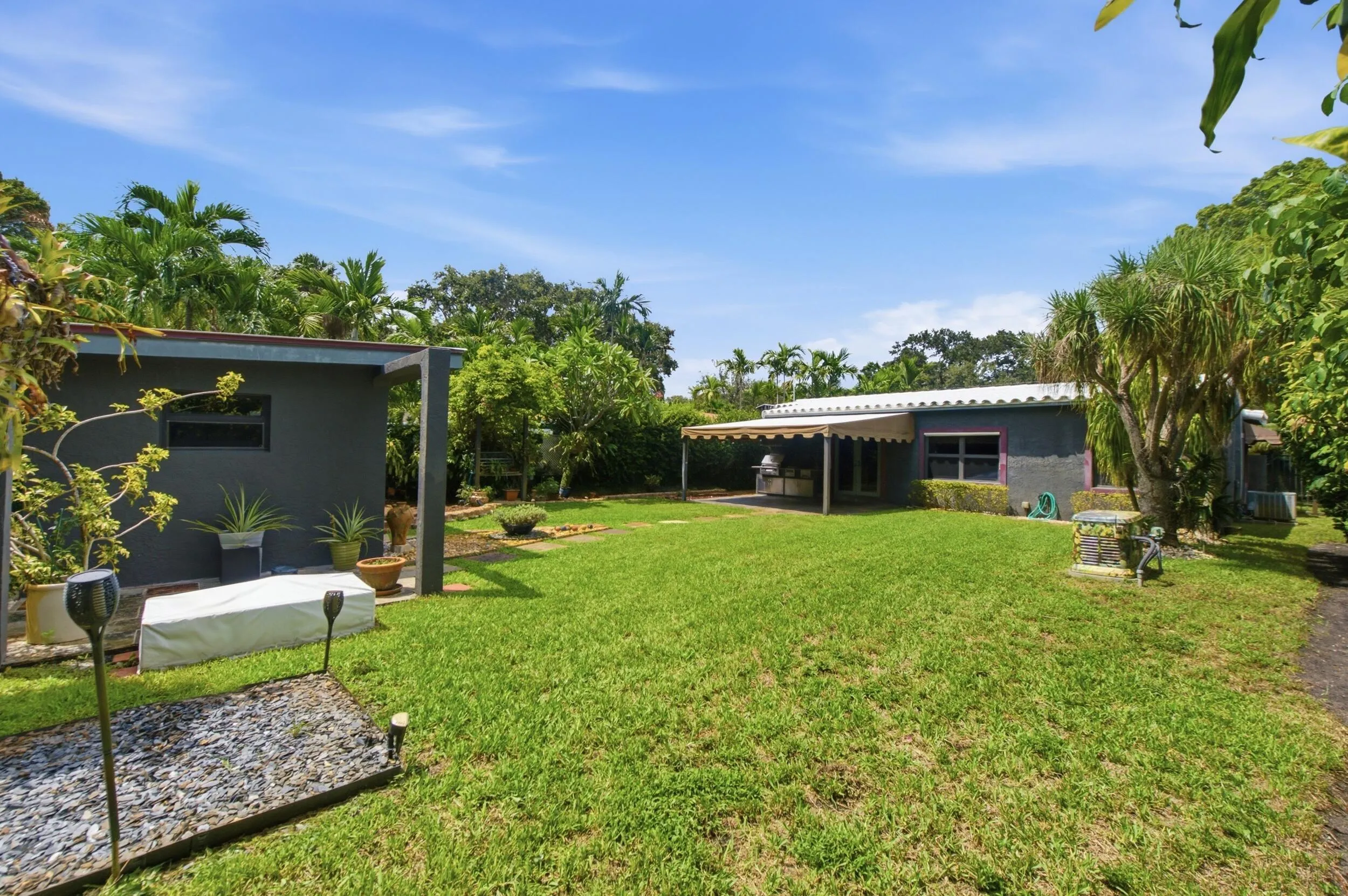 Expansive green lawn with mature trees and a shaded patio area