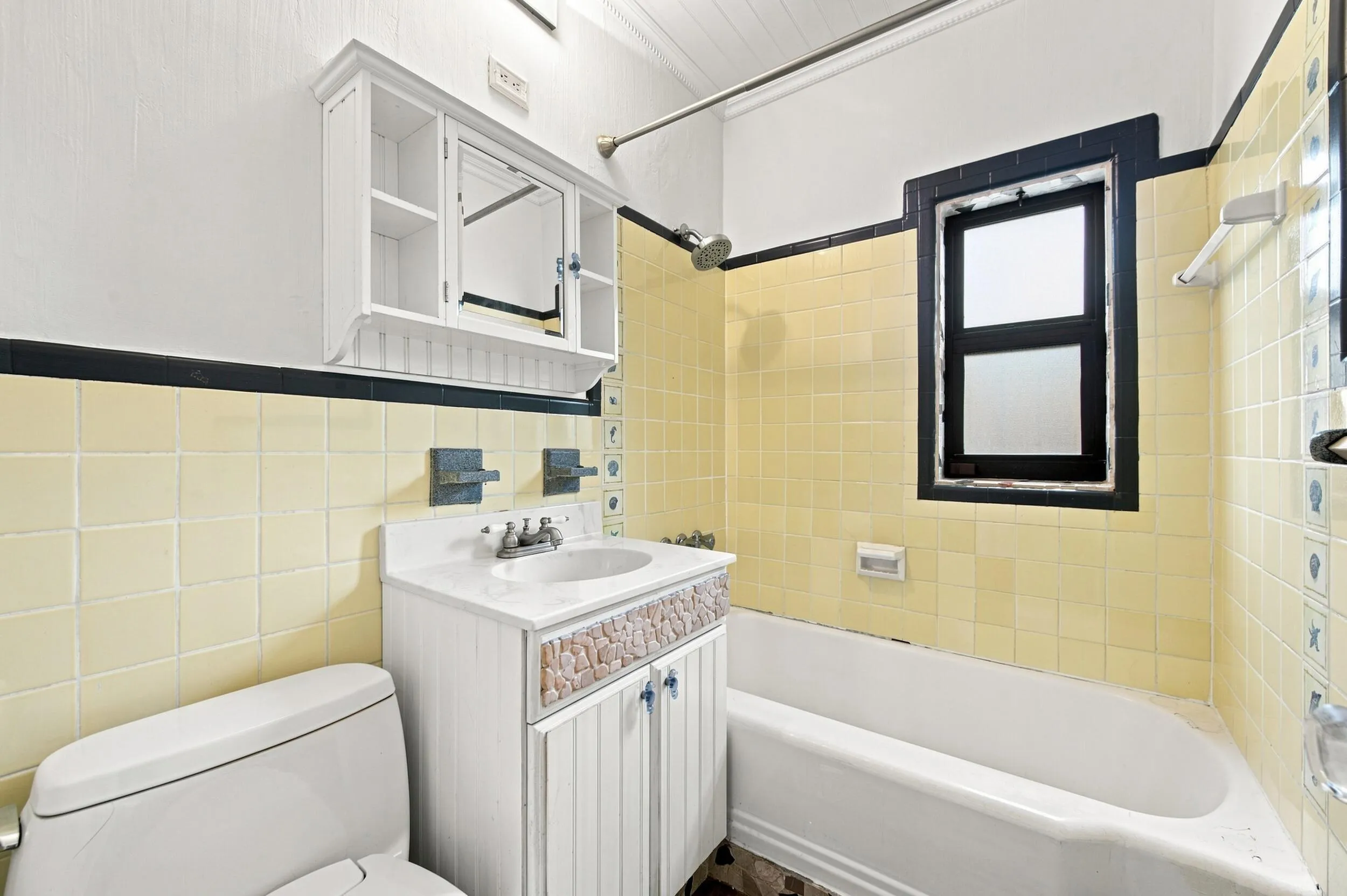 Bathroom featuring a white vanity with a built-in sink, medicine cabinet, and a shower-bathtub combination with yellow wall tiling
