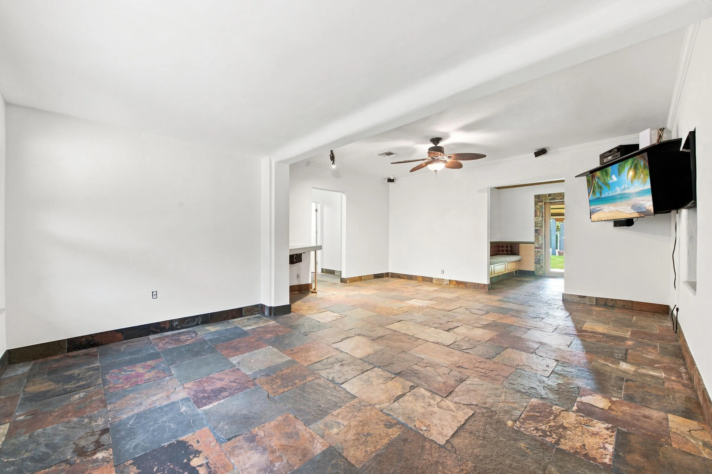 Spacious room featuring multi-toned stone flooring and a ceiling fan