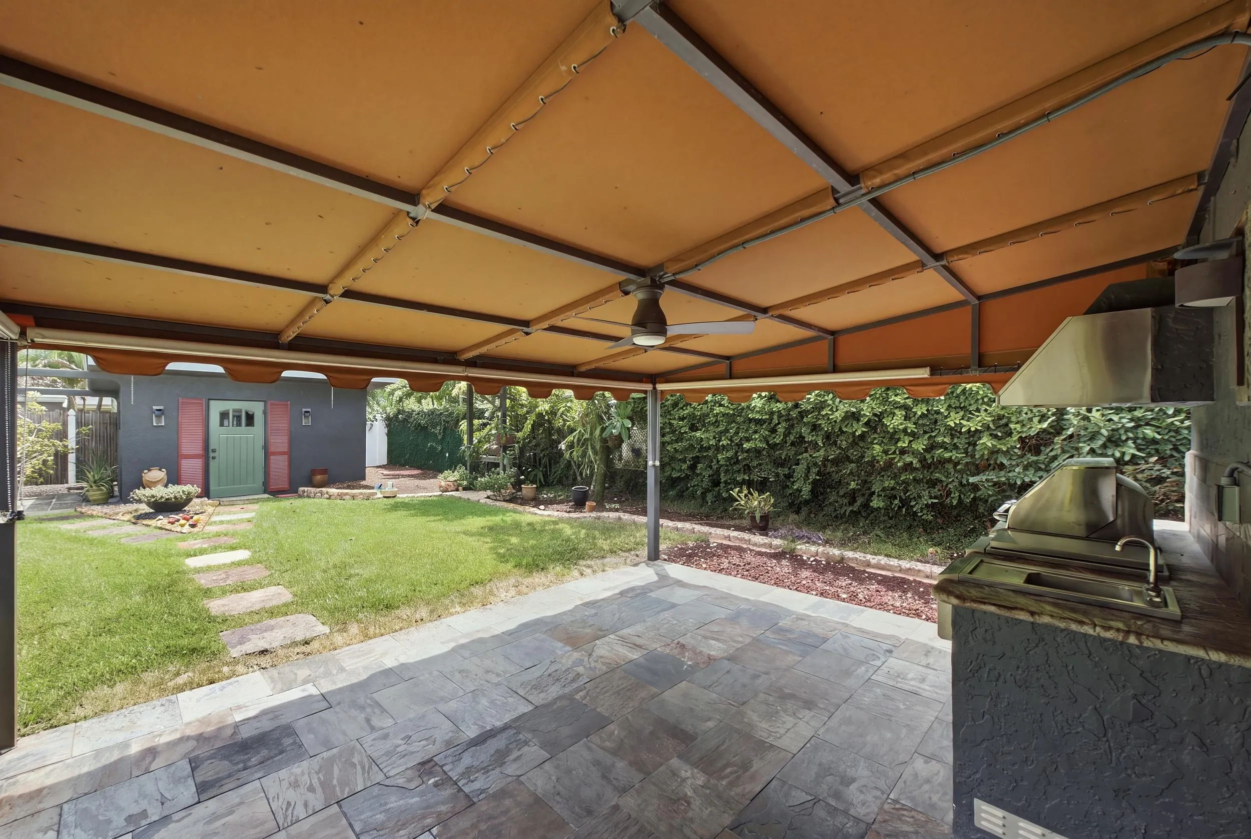 Covered patio featuring an outdoor kitchen with an integrated grill, a ceiling fan, and slate tile flooring