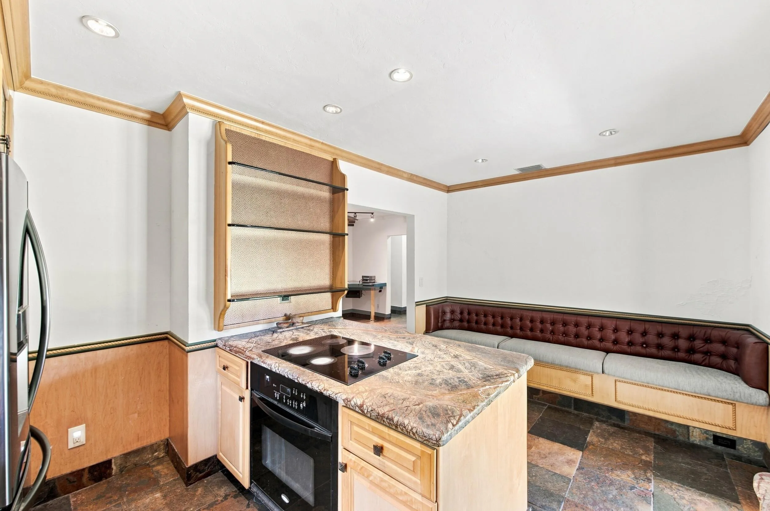 Built-in seating with upholstered cushions, a kitchen island with cooktop, built-in oven, wood-finish cabinetry, and recessed lighting