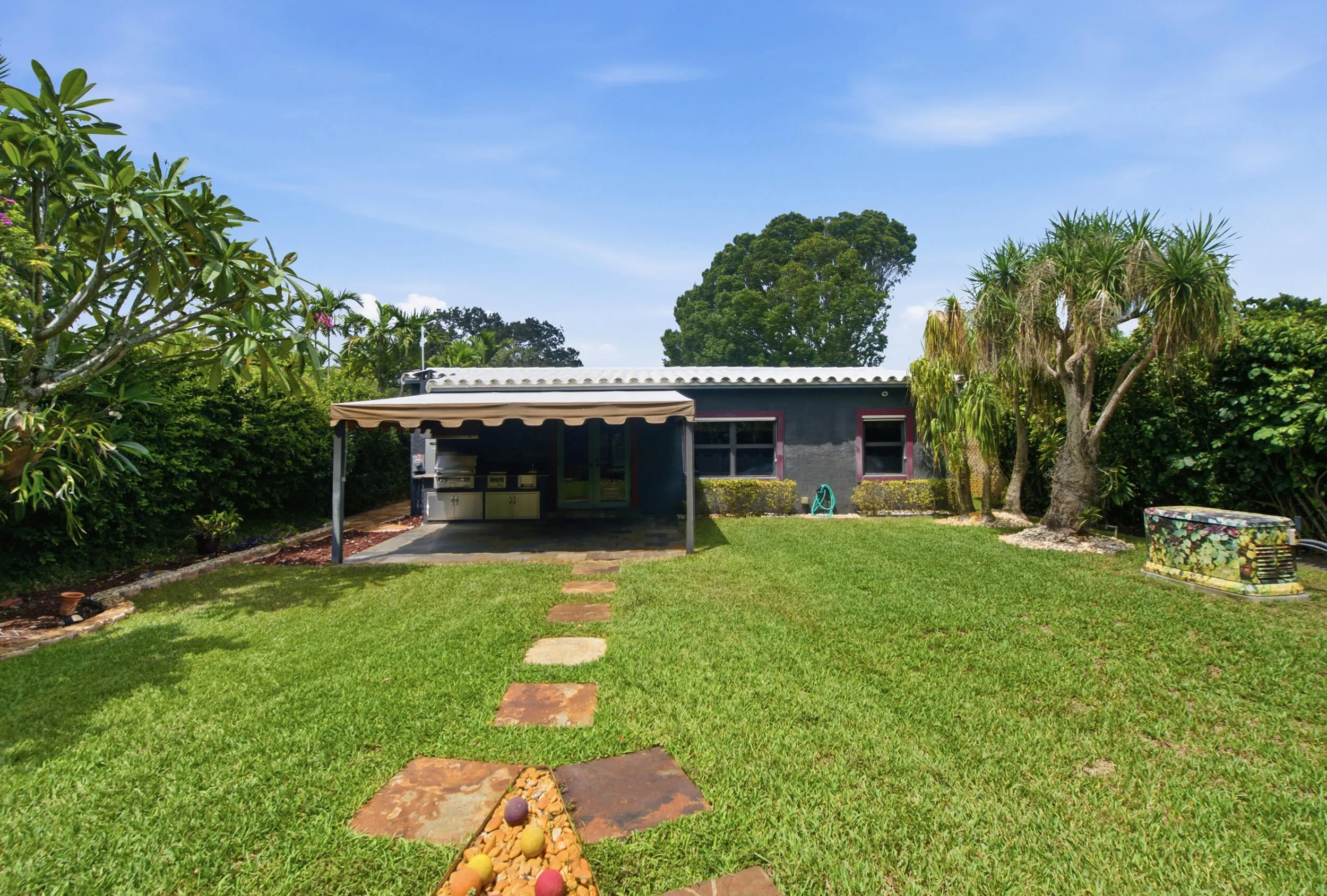 Expansive backyard with a manicured lawn, established landscaping, and a covered patio