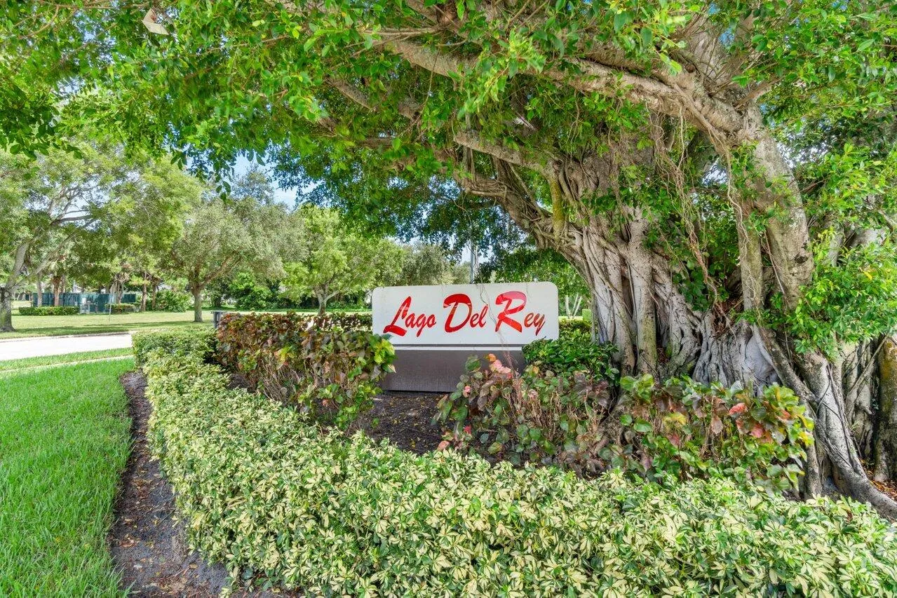 Lago Del Rey community entrance sign surrounded by mature landscaping.