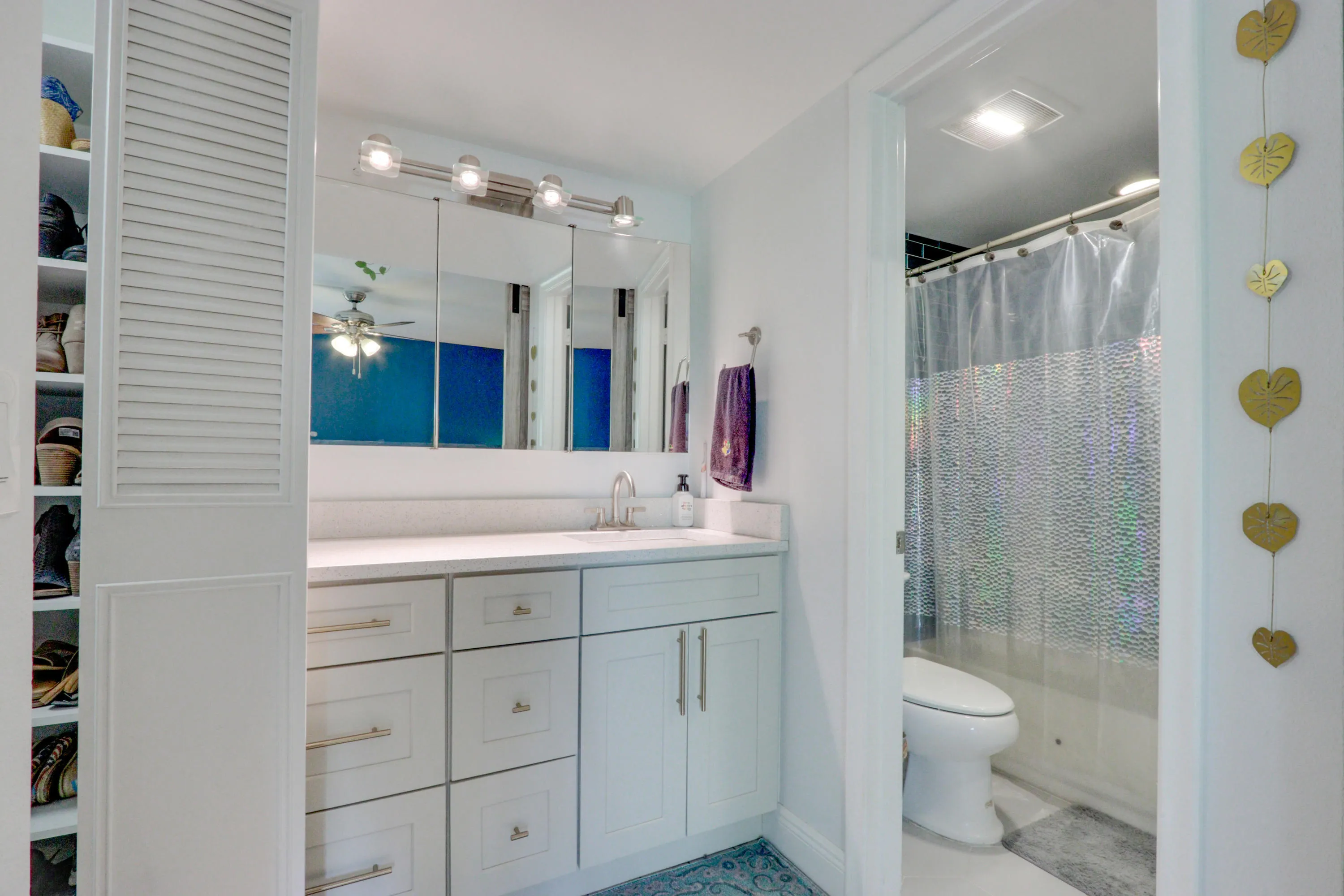 White vanity with shaker-style cabinetry, a light-toned countertop, and a mirrored medicine cabinet